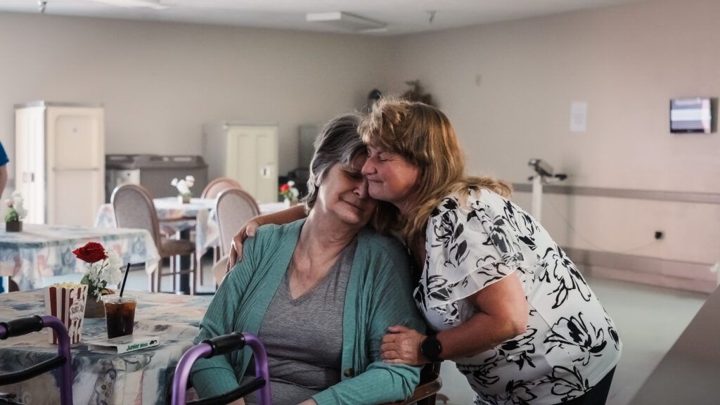 A nurse hugs a long term care resident at a skilled nursing facility nursing home