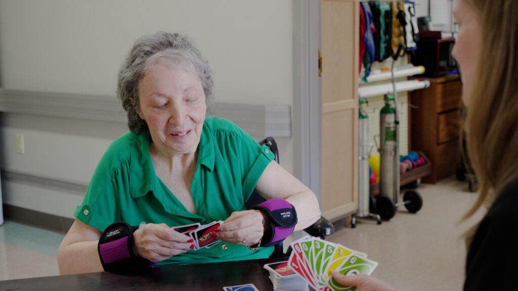 A respite care patient is playing cards with a nurse at a skilled nursing facility